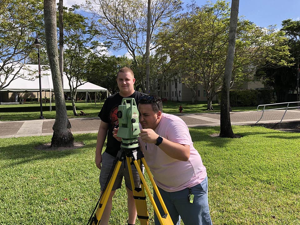 FAU students standing on campus with their survey tools 3