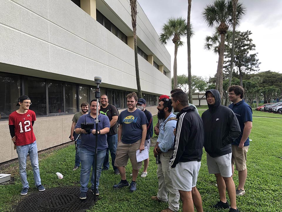 FAU students standing on campus with their survey tools 2