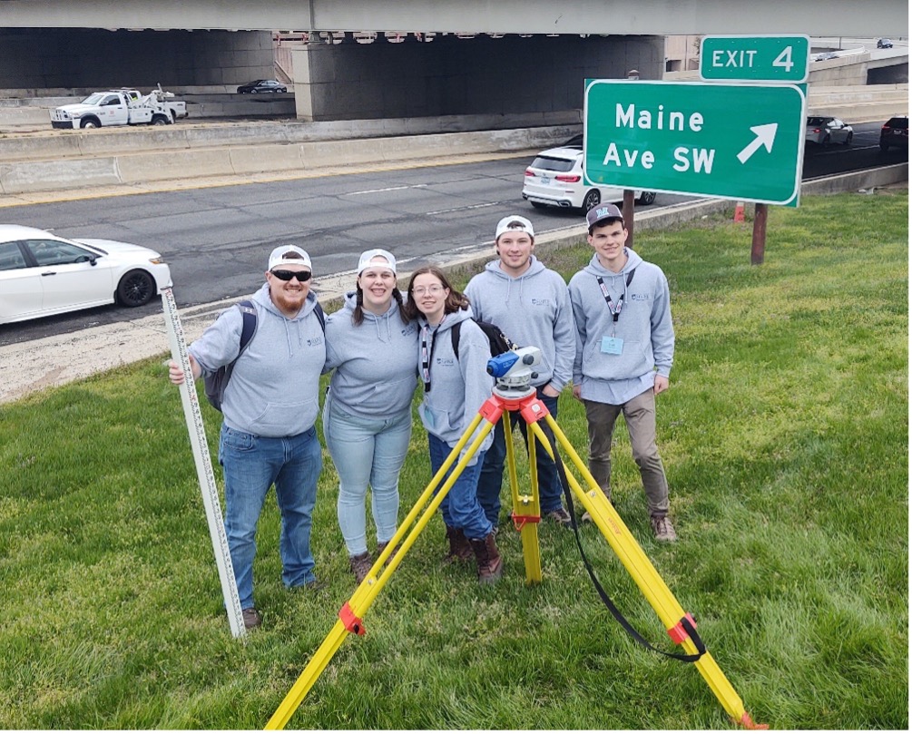 University of Maine students standing on side of highway with surveying tools